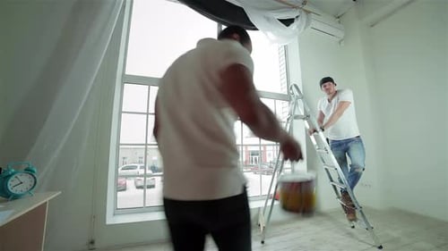 Two Men Working Together Painting Indoors