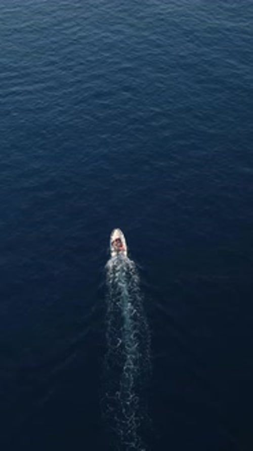 Vertical Video Lone Fisherman on a Boat Surrounded By Azure Waters Casting a Fishing Line