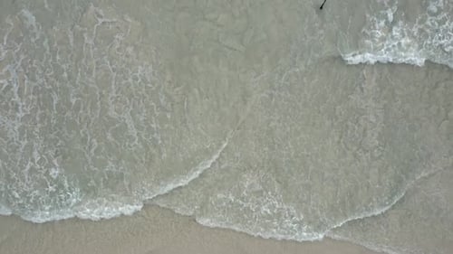 Aerial Overhead of Waves Crashing at the Beach on a Clear Day.