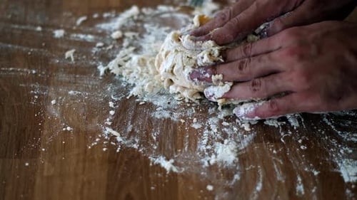 Handwerkliche Hände kneten Teig auf Holzoberfläche für die traditionelle Nudelherstellung