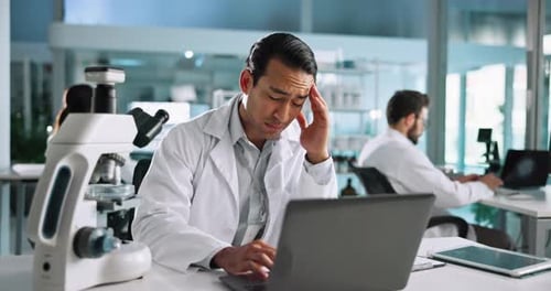 Scientist Using Laptop has a Headache in Lab