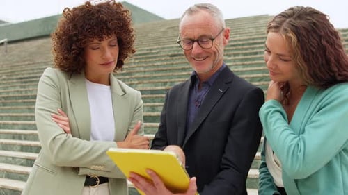 Business Team Collaborating on Tablet Outside Office