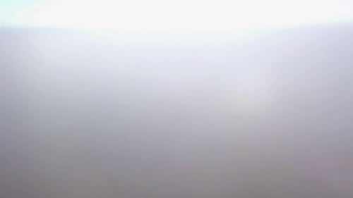 High altitude aerial shot moving up through cloud layer. Misty foggy cloud. Bright sun after drone r