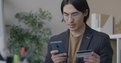 Asiatischer Geschäftsmann nutzt Smartphone und Kreditkarte und konzentriert sich auf die mobile App für E-Commerce und Finanzen in