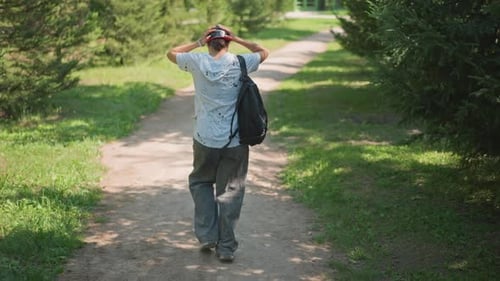 Teenager Walking on Path in Sunny Green Park