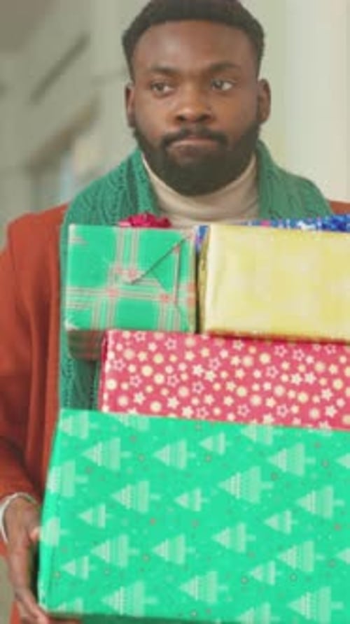 Person with Presents Shopping During Holidays Individual Carrying Wrapped Gifts in Festive Mall