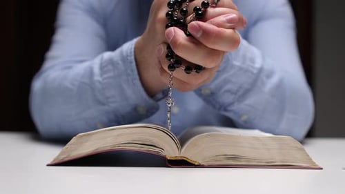 Man Holding Rosary with Bible in Close Up