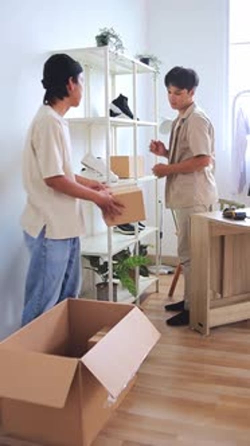 Two young entrepreneurs exchanging package in modern office workspace for e-commerce business