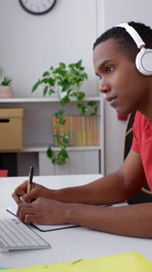 Young Adult Writes in Notebook at Desk