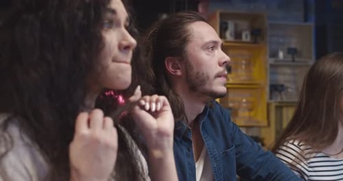 Caucasian Guys and Girls Sitting at Pub with Beer in Evening and Watching Sport Match on TV Friends