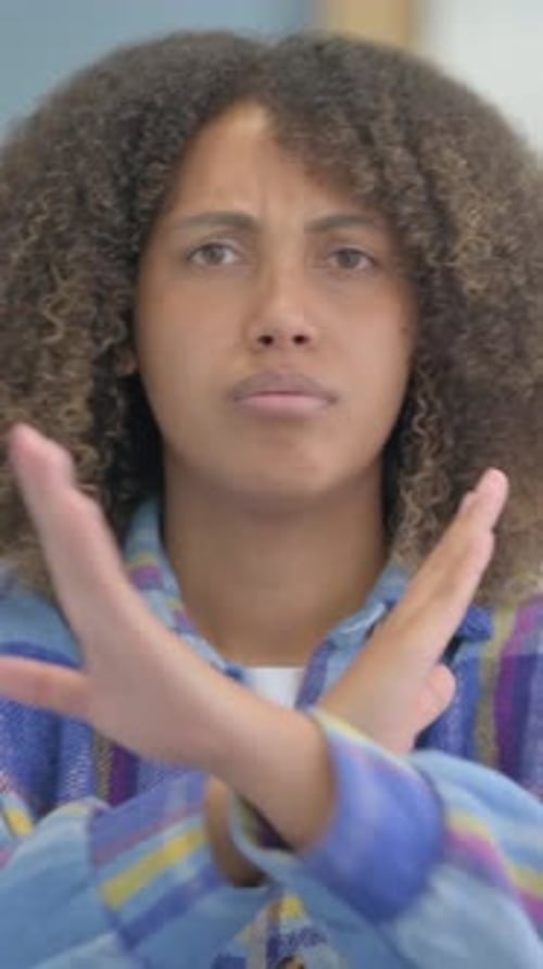 Young Woman Gesturing No with Crossed Arms Indoors