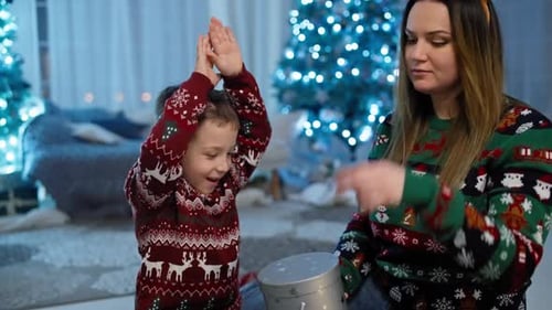 Boy Receives Gift With Christmas Tree in Background