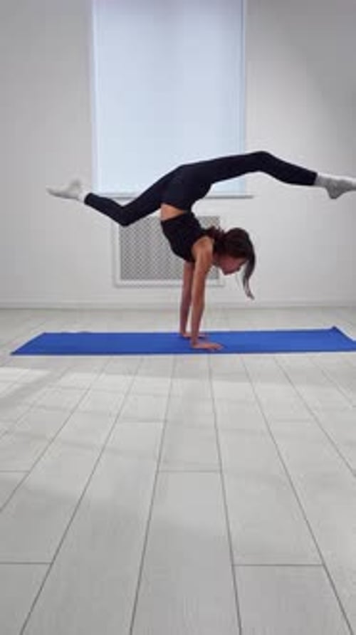 Jeune femme pratiquant des exercices de yoga avancés à l'intérieur