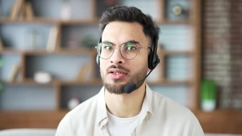 Webcam view. Confident businessman in headset talking on video call sitting in home office looking