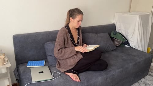 Young Woman Sitting on Sofa at Home Reading Notes and Planning Tasks Casual Lifestyle Scene Showing
