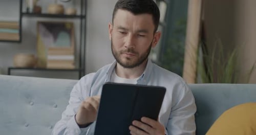 Man Using Tablet on Couch at Home