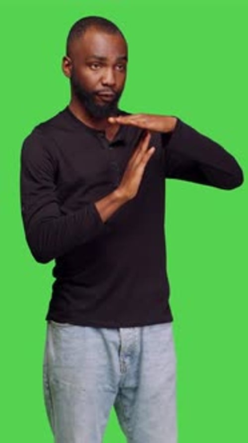 Vertical Video Front View of Confident Casual Man Expressing Timeout Gesture in Studio