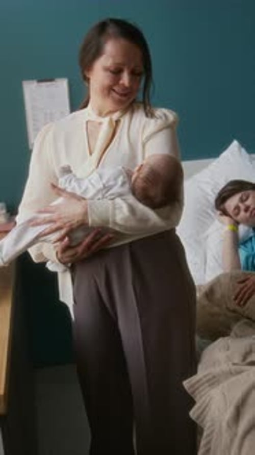 Granny Rocking Baby in Arms in Maternity Hospital Room