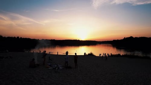 Shooting From Quadcopter of Silhouettes of People Relaxing on the Beach Next to Campfire and