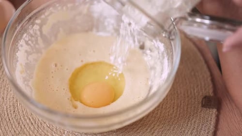Adding Flour to a Bowl of Batter with Egg