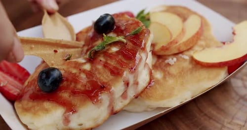 A Man's Hand Serves a Breakfast in the Morning and Cuts It with a Knife Pancakes