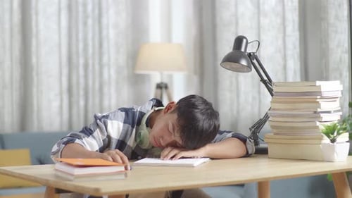 Tired Asian Teenager Yawning And Sleep On The Table At Home After Doing Home Work