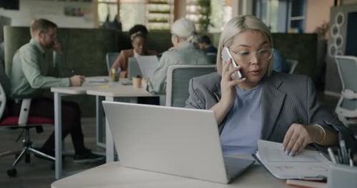 Woman Works and Talks on Phone in Office