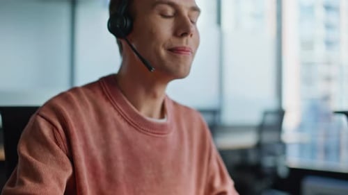 Young Adult Typing on Computer Wearing Headset