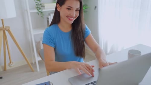 Smiling Woman Typing on Laptop at Home