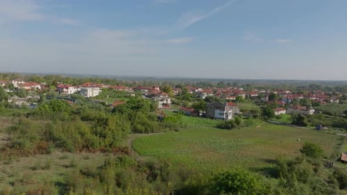 Aerial Views Showcase Green Fields and Charming Houses Nestled in a Valley Beneath a Bright Blue Sky