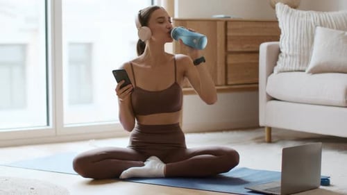 Young Woman Relaxing with Phone after Workout