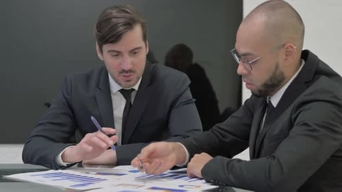 Businessmen Collaborating on Data Analysis at Conference Table