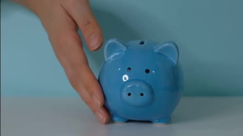 Piggy Bank Business Concept A Hand is Putting a Coin in a Piggy Bank on a Blue Background Saving