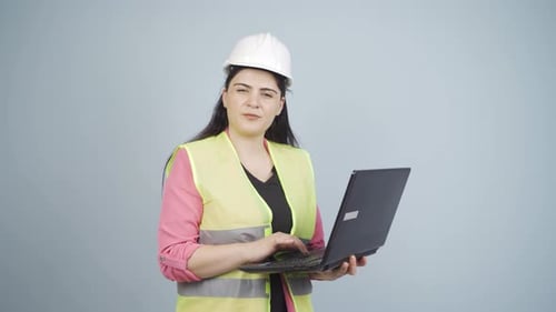 Ingenieur hält Laptop in der Hand und lacht in die Kamera.