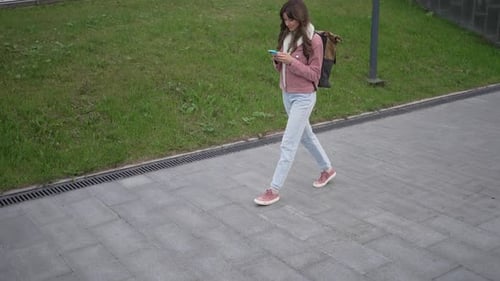 Young Woman Walking and Using Smartphone on the Street