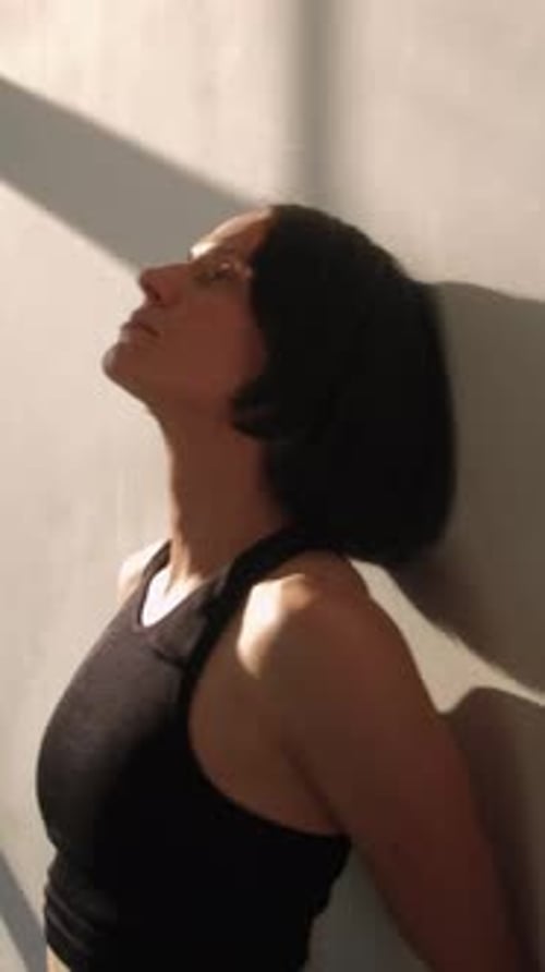 Woman Leaning Against Wall in Sunlight