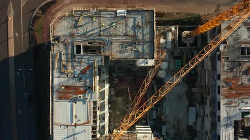 Top Down View of Building Construction with Tower Cranes and Workers