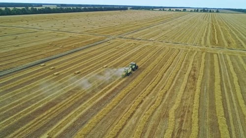 Hay Baler Traktor fährt über das Feld, sammelt Strohhalme und macht die Ballen Luftbild in