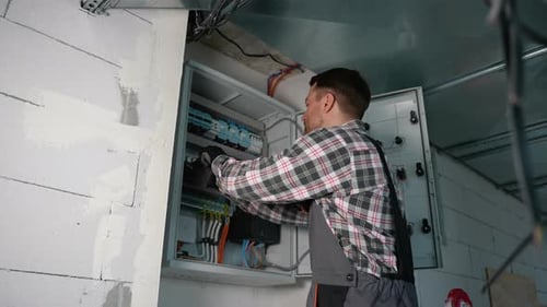 Electrician Working on Breaker Box with Screwdriver