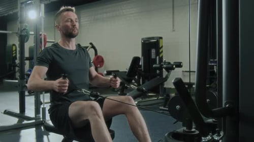 Man Exercising on Rowing Machine in Gym for Strength Training