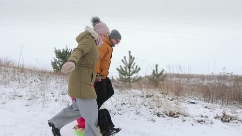 Family Father and Mother Sledding Daughter Holding Hands Winter Fun
