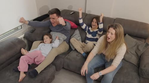 Familia disfrutando del tiempo juntos en el sofá vitoreando y haciendo cosquillas