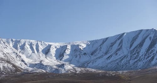 Timelapse of Sun Movement on Crystal Clear Sky Over Snow Mountain Top Yellow Grass at Autumn Meadow