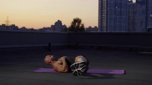 Man Doing Crunches on Rooftop at Sunrise