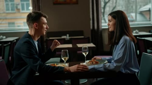 Date in the hotel restaurant dinner man and woman drink white wine in glasses and taste food