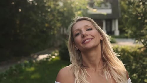Attractive Woman Smiling in Sunlit Suburban Yard