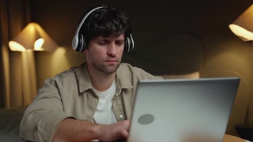 Young Adult Using Laptop with Headphones at Home