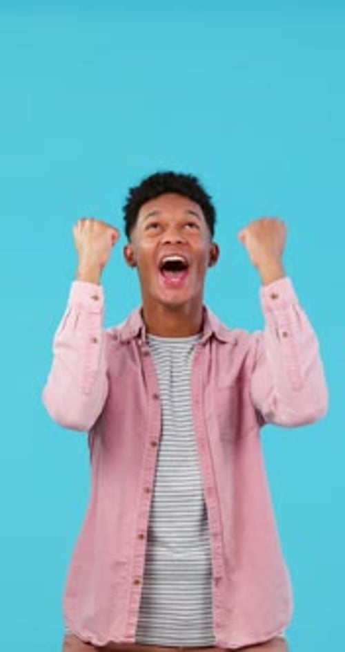 Man, excited about winning and cheers in studio, happiness and celebration with fist isolated