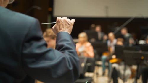 A Famous Elderly Gentleman in Suit Is Conducting Band Pit Collective Looking