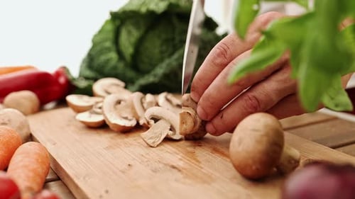 Hands Slice Mushrooms on a Cutting Board